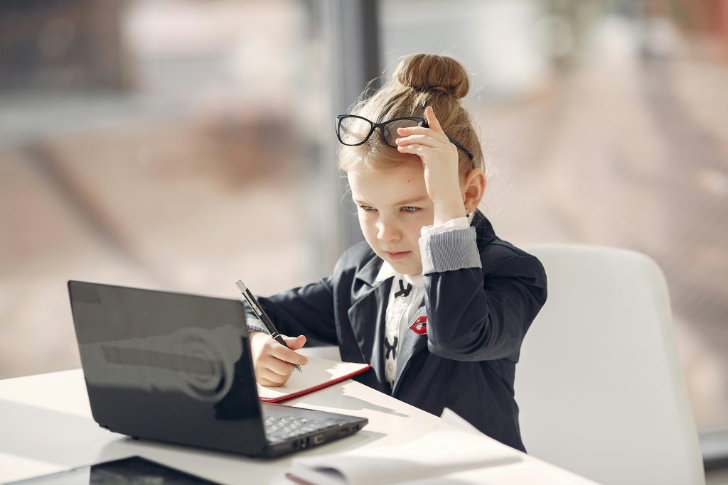 pexels photo 3874385 3874385 A young girl dressed in business attire using a laptop, symbolizing childhood ambition and learning.
