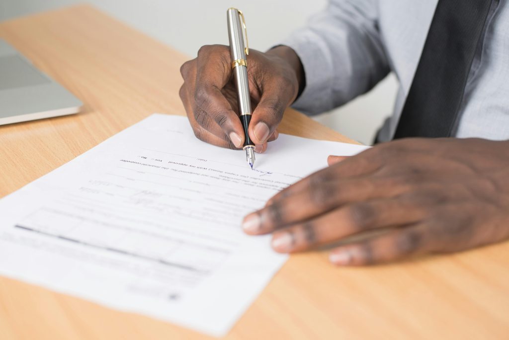 pexels photo 955389 955389 Close-up of a businessman signing a contract at an office desk.